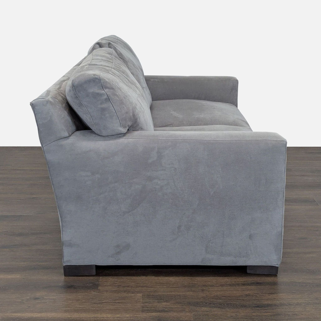 Modern gray sofa by Crate and Barrel features soft fabric, wide padded arms, and comfortable seat for three.