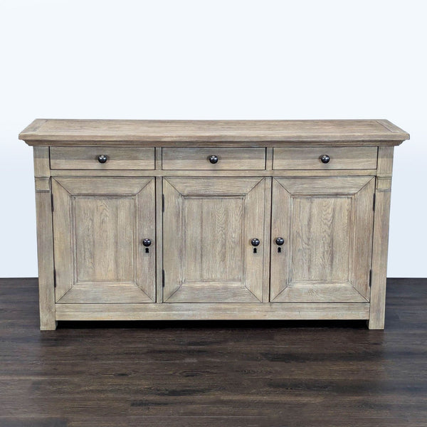 1. Pottery Barn sideboard with three drawers and four panel doors in a light wood finish, front view.