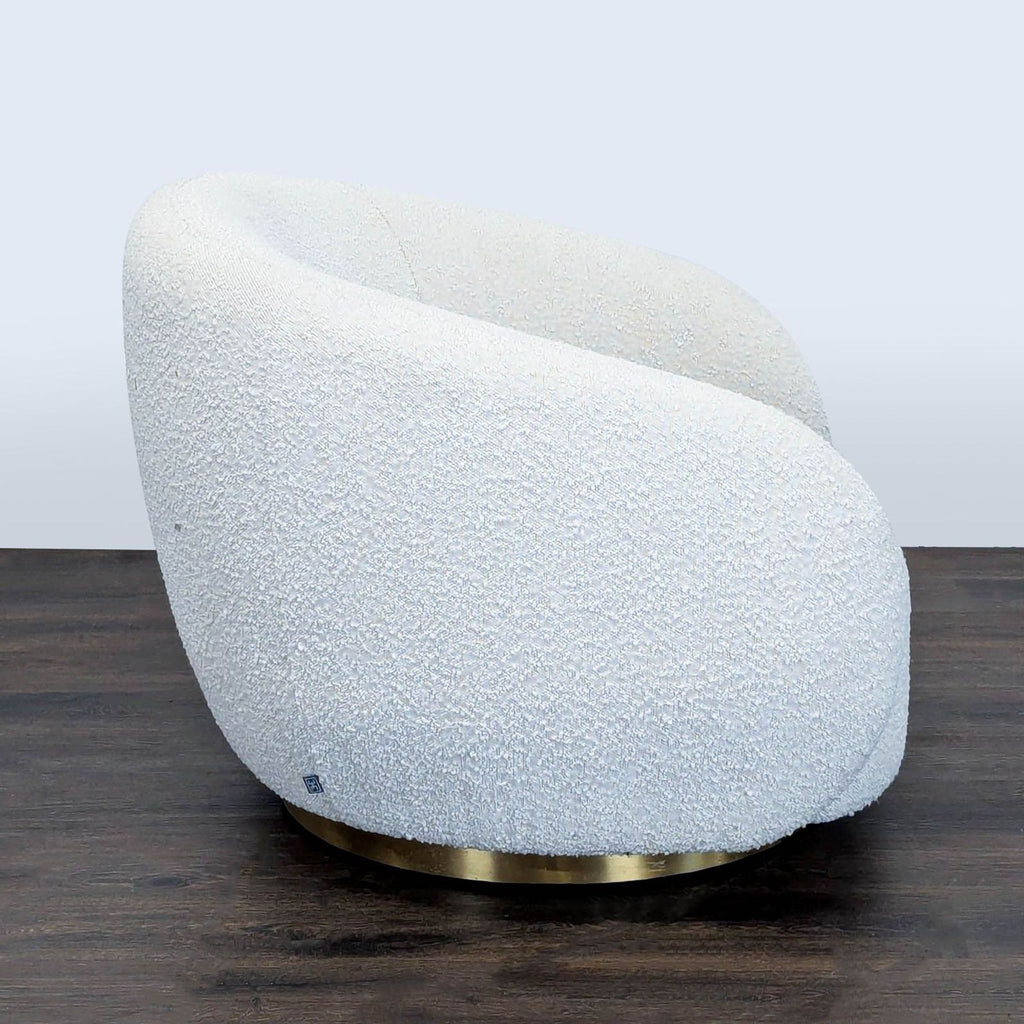 2. Side view of a soft white bouclé Eichholtz lounge chair with plush curves and brass swivel base.