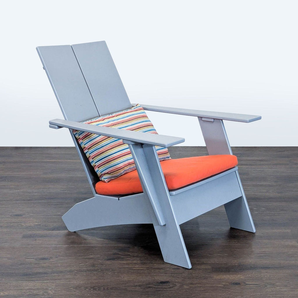 Contemporary gray Room & Board chair with an orange cushion and striped pillow, suitable for indoor or outdoor use.