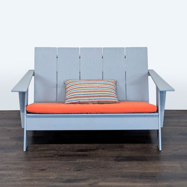 Modern Room & Board loveseat chair with light gray frame, orange cushion, and striped pillow for two people.