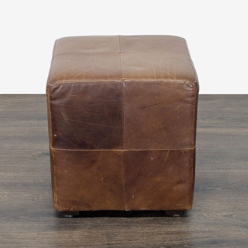 1. Square brown leather ottoman from Restoration Hardware with visible seams, shown on a wooden floor.