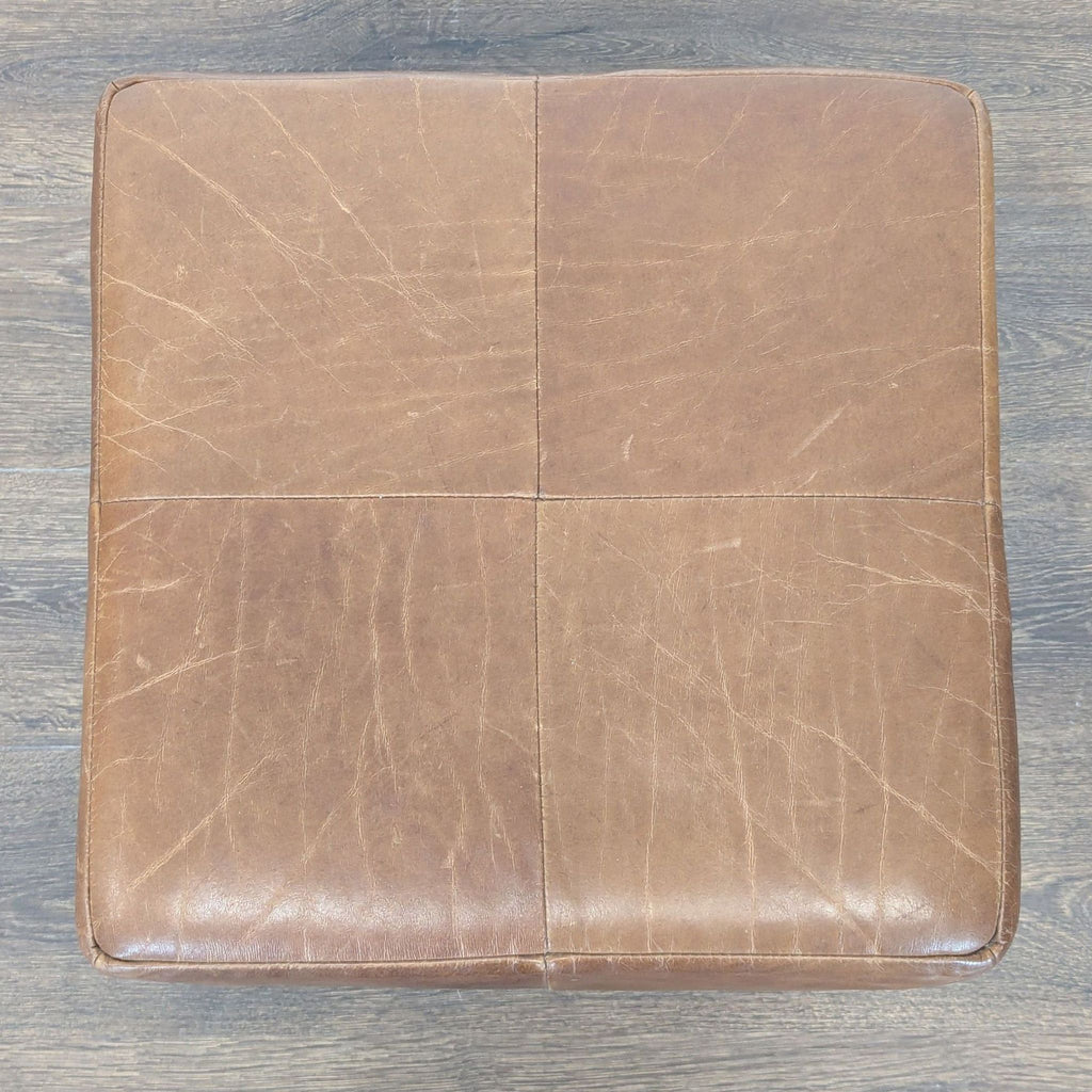 3. Top-down view of a square leather ottoman from Restoration Hardware, showing four stitched sections.