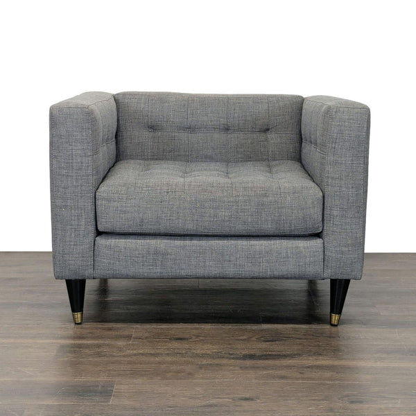 Modern lounge chair with tufted gray fabric, black wood legs, and gold tips, ideal for stylish living rooms.