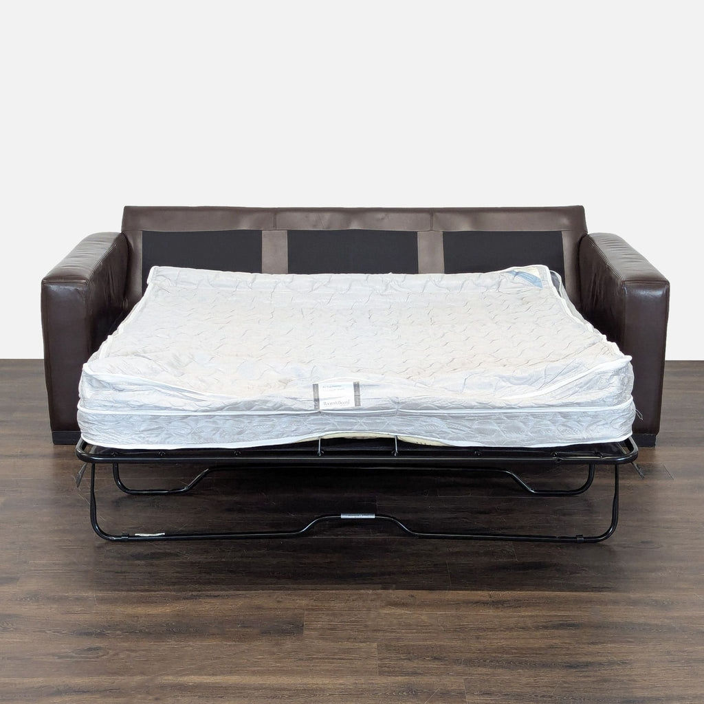 Brown leather Room & Board sleeper sofa featuring supportive cushions and a space-saving pull-out bed for guests.