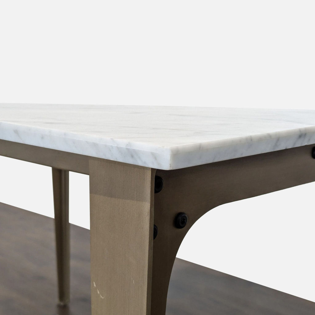 Modern French-inspired dining table featuring a smooth grey-veined marble slab and tapered brass-finished metal base.