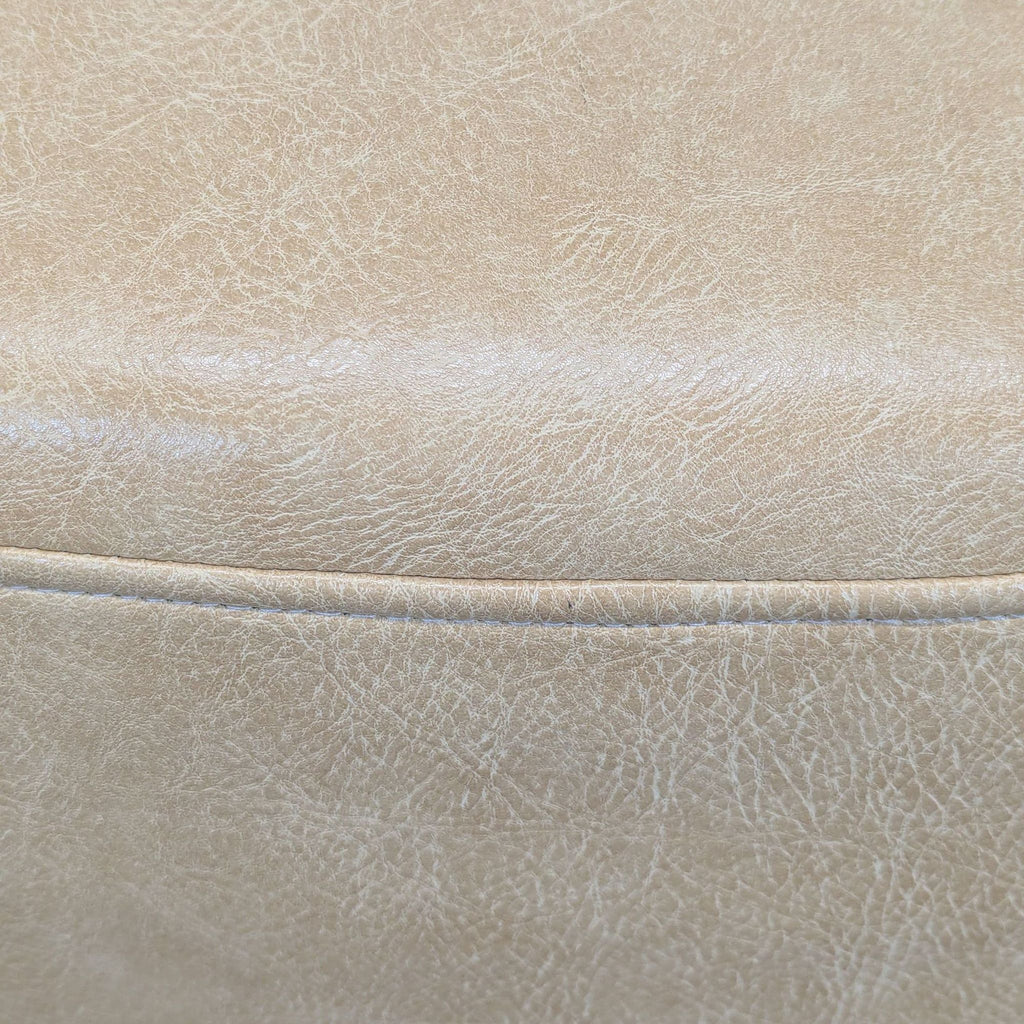 3. Close-up of tan faux leather upholstery on an ottoman, showing texture and stitching detail.