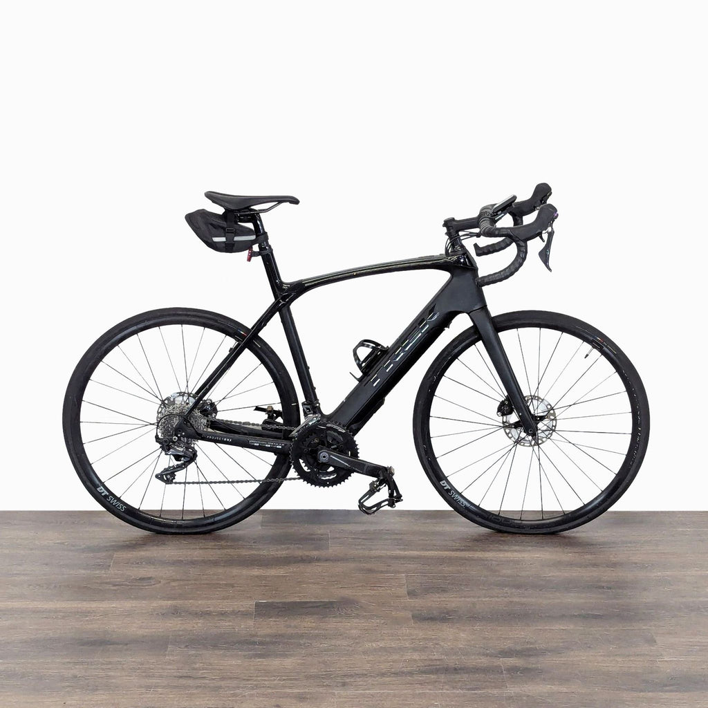 Black Trek road bike featuring a lightweight carbon frame, disc brakes, and a convenient saddle bag for essentials.
