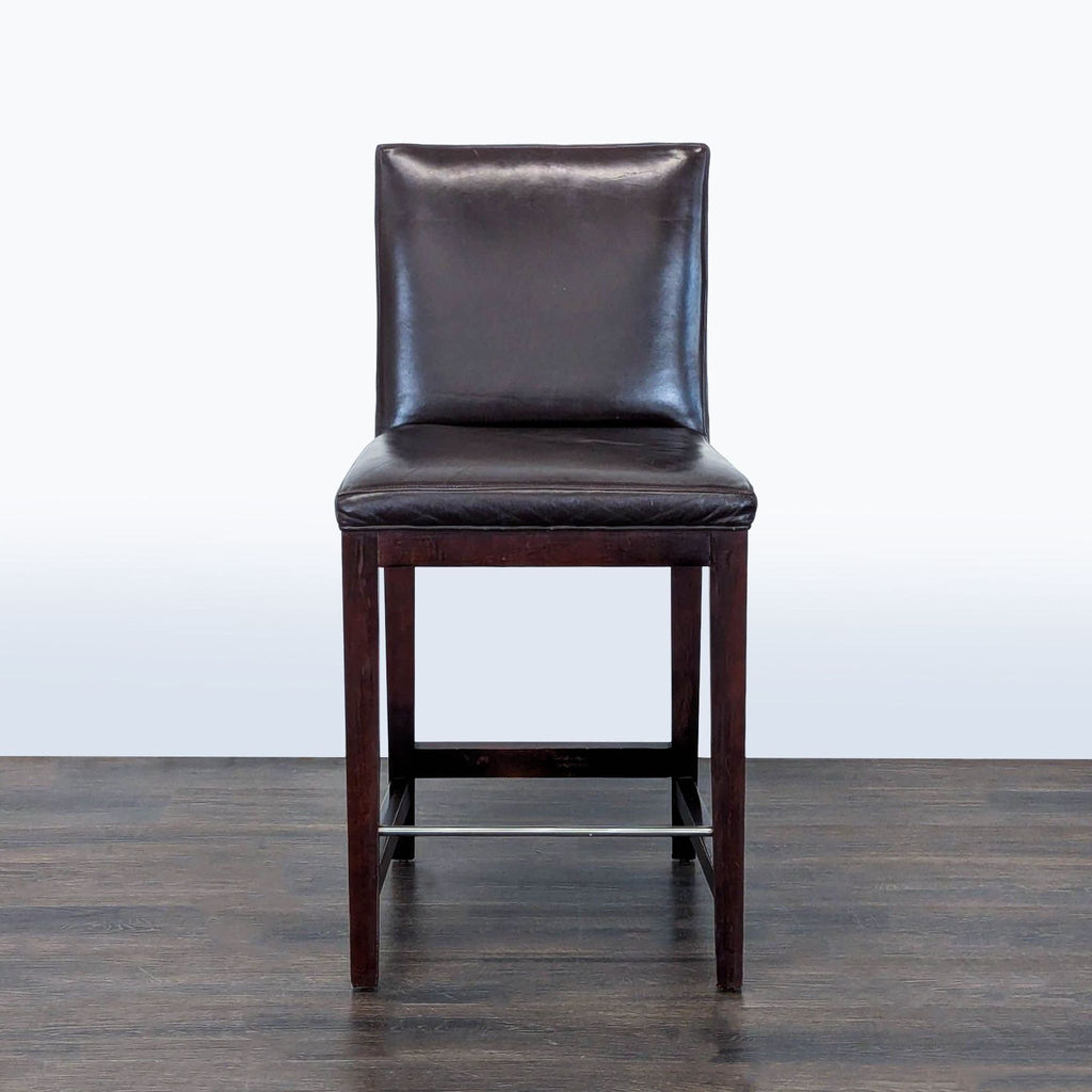 Modern leather-upholstered stool with hardwood frame and steel footrest by Room & Board.