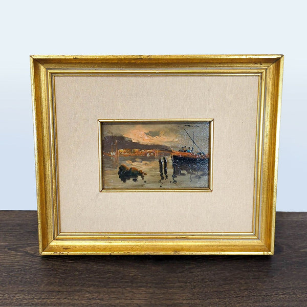 Oil painting of a tranquil harbor at sunset with a boat and reflections, framed in gold with a fabric mat.