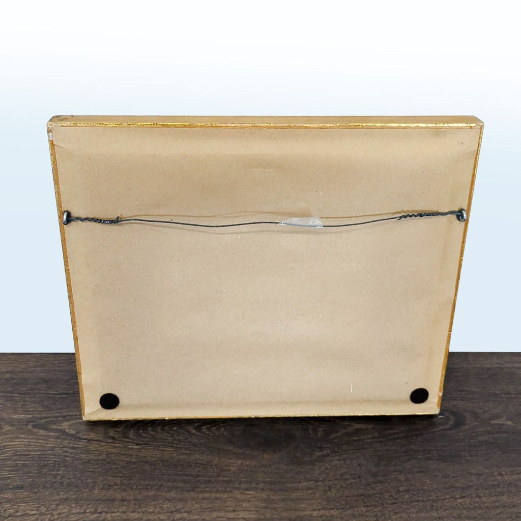 Small, detailed harbor painting featuring warm colors, a moored boat, and elegant gold-toned framing.