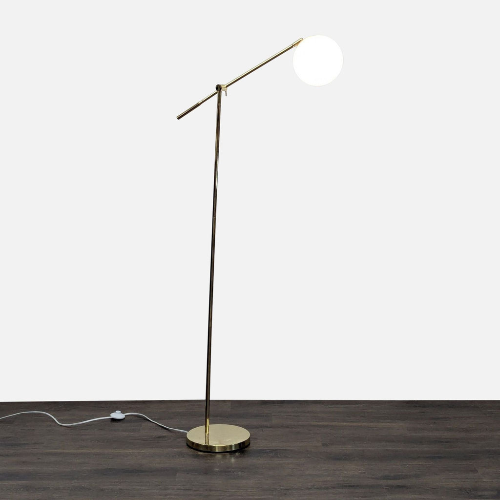 Brass floor lamp with frosted glass globe, round base, and adjustable arm for directed lighting.