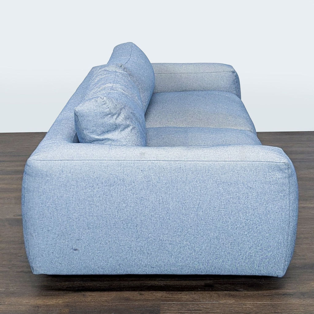 Four Hands sofa with light blue fabric, wide armrests, and plush seating, ideal for contemporary living rooms.
