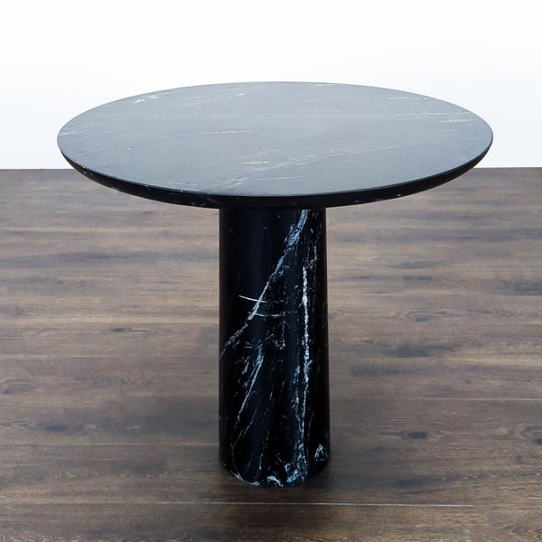 Honed black marble bistro table with a sculptural pedestal and rounded top by CB2 for dining spaces.