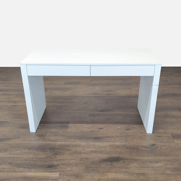 Sleek white CB2 desk with two drawers, perfect for modern home offices or study spaces.