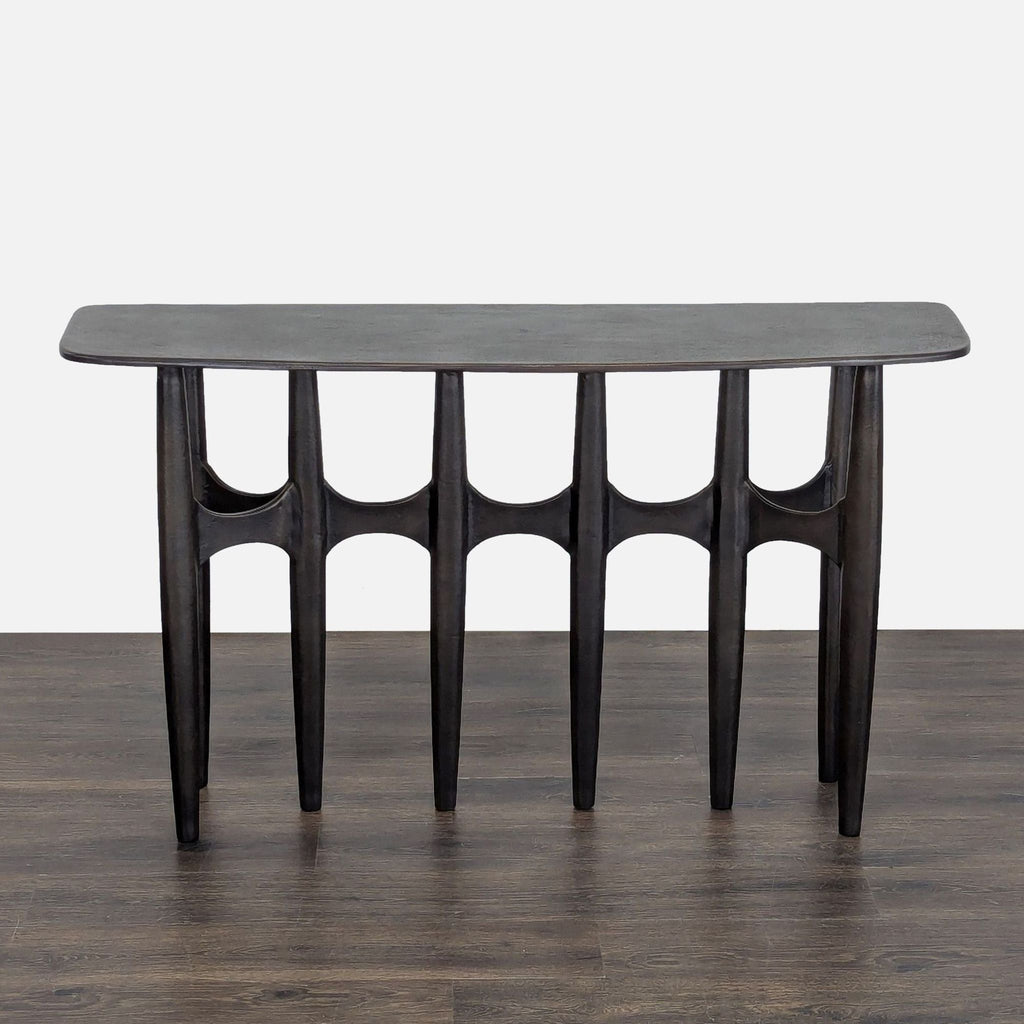 Brutalist-style console table by CB2, featuring textured dark bronze cast aluminum with a curved front.  