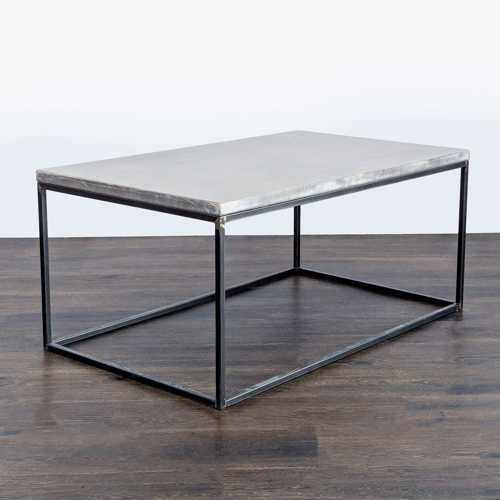 2. Modern coffee table featuring a grey concrete slab top and thin black metal legs, angled side view.