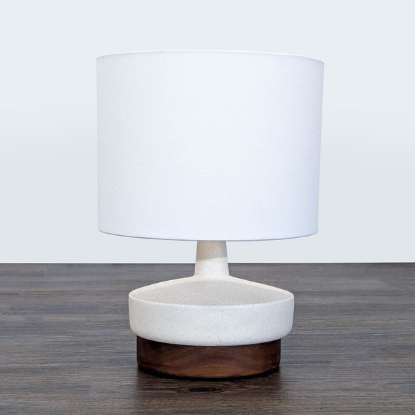1. West Elm table lamp with a smooth white ceramic body, wooden base, and simple white drum shade on a dark surface.