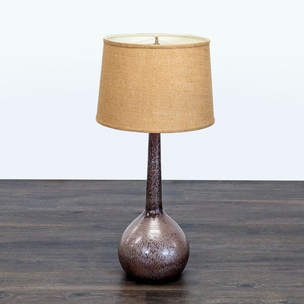 Modern ceramic table lamp with a textured brown base and a natural fabric shade for warm lighting.