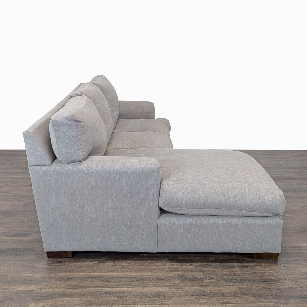 Spacious sectional sofa in soft gray fabric, featuring a wide chaise and cushioned support for living rooms.