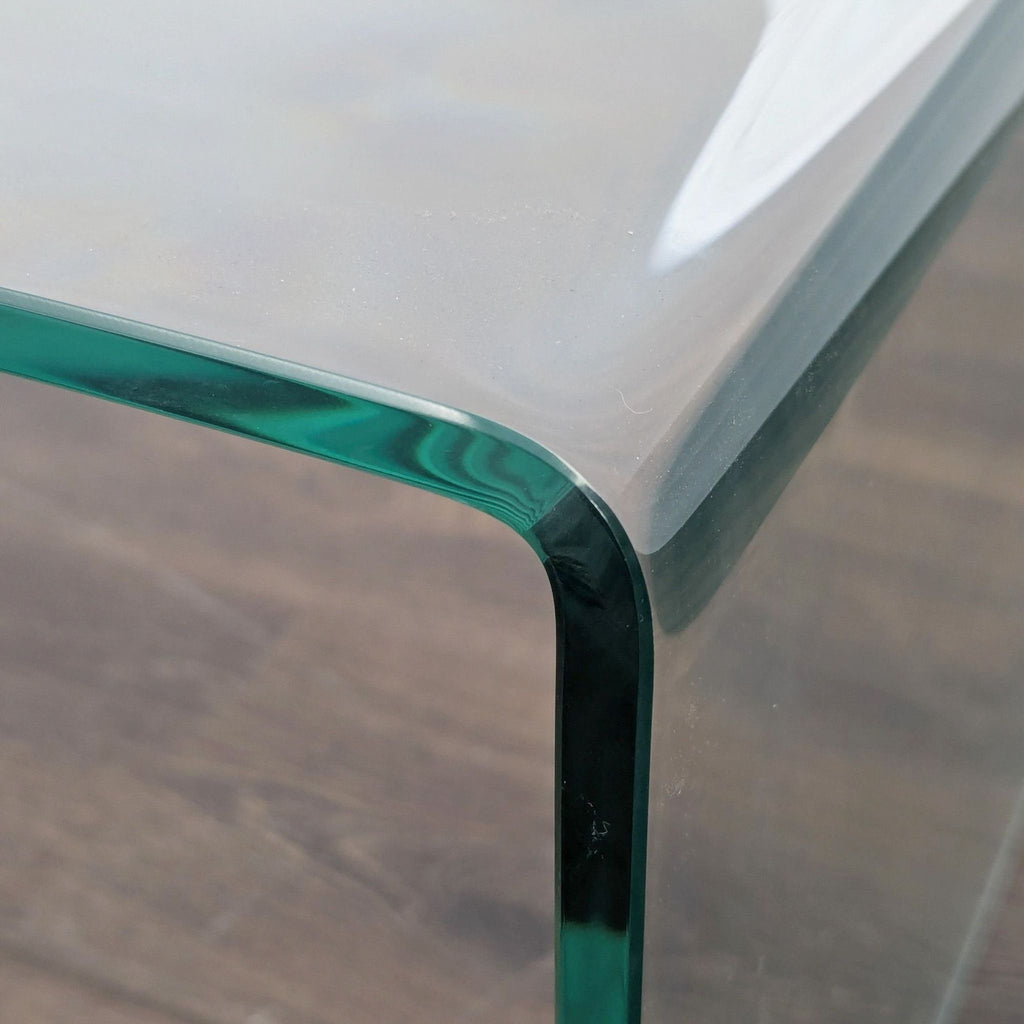 Close-up of the Ivy Bronx glass coffee table’s rounded corner, showing its smooth glass edge.
