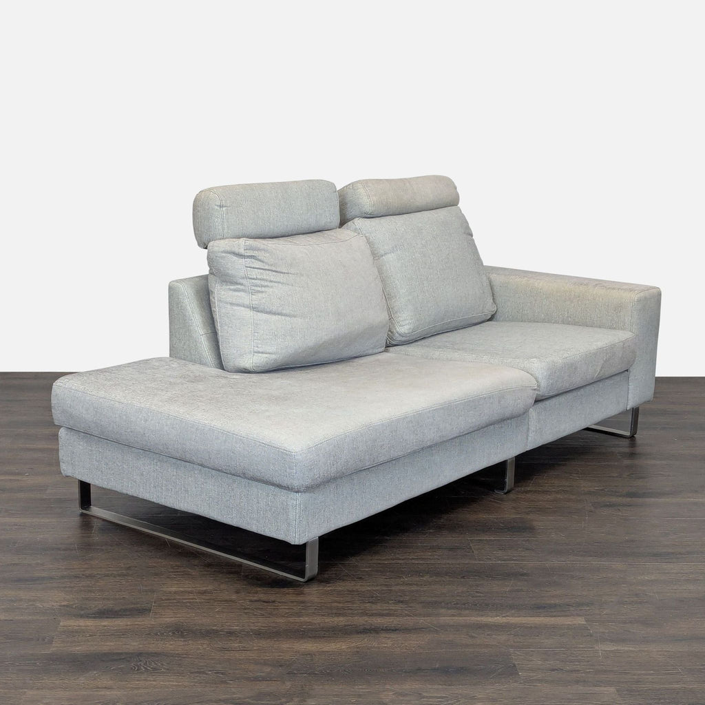 Modern BoConcept sectional sofa in soft gray fabric with sleek metal legs and adjustable headrests for enhanced comfort.