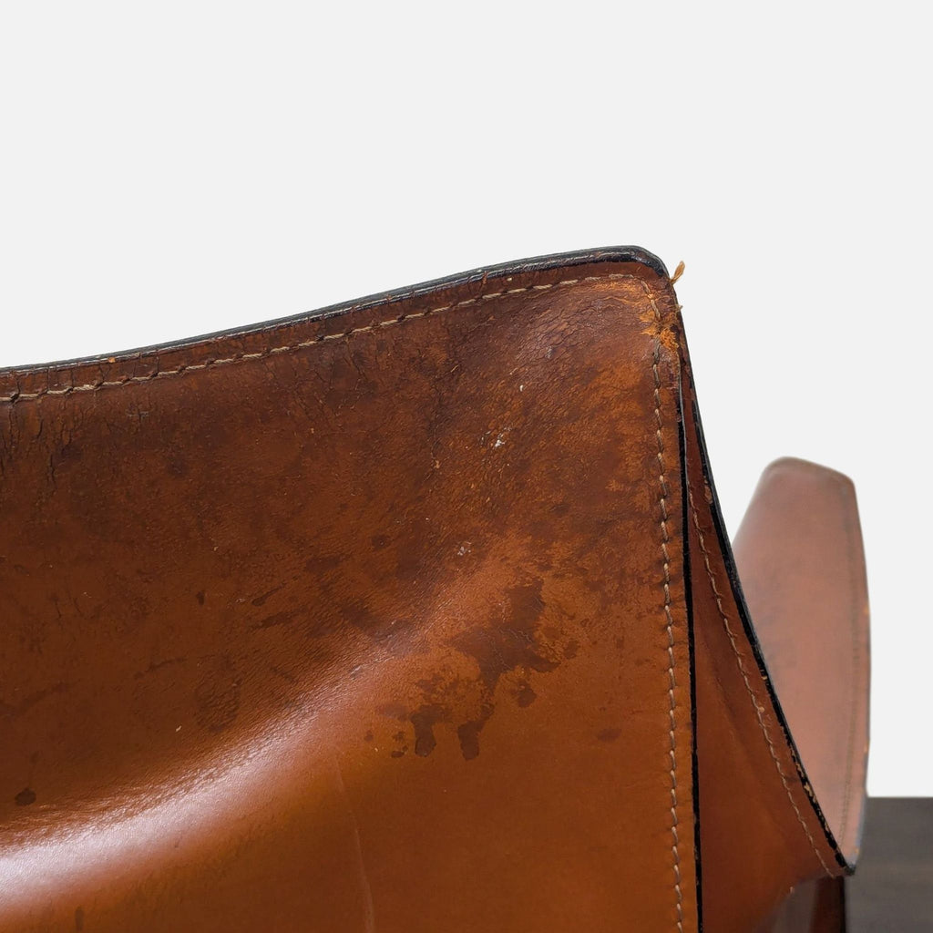 Close-up of a Cassina Cab dining chair showing precise leather stitching and seamless armrest-to-back design.  