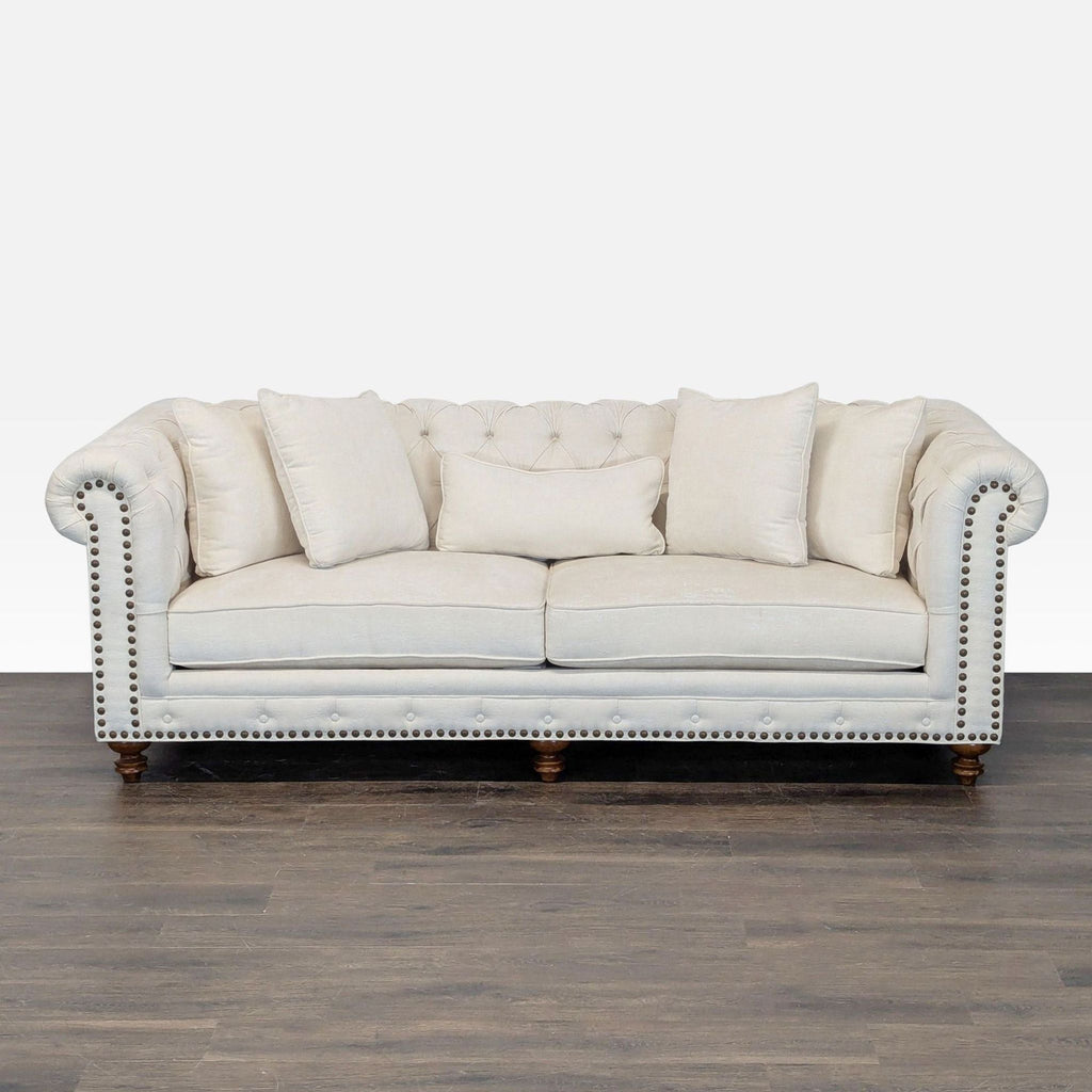 Elegant cream 3-seat Chesterfield sofa with button tufting, rolled arms, and nailhead trim for stylish comfort.