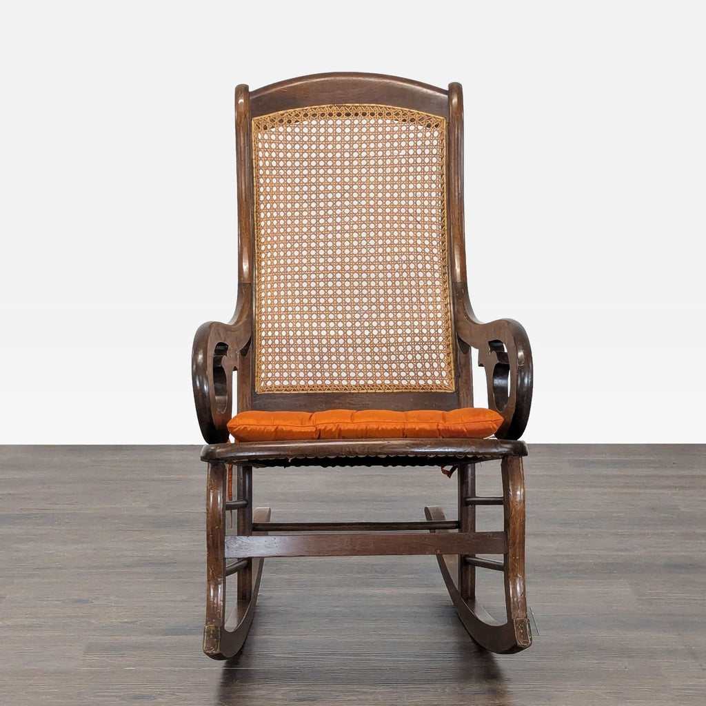 Classic bentwood rocking chair with cane back and orange cushion, ideal for cozy relaxation in any room.