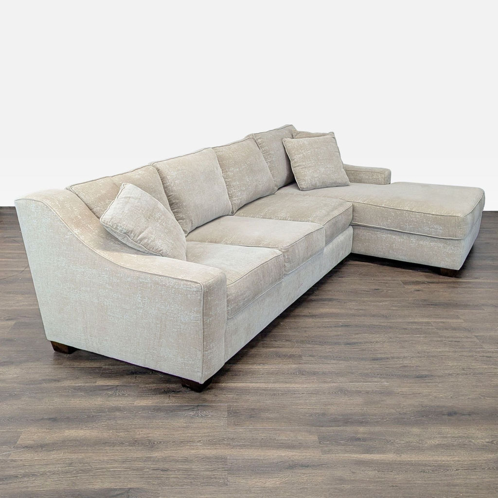 Spacious beige sectional featuring a chaise, three cushions, and soft fabric for modern living room comfort.