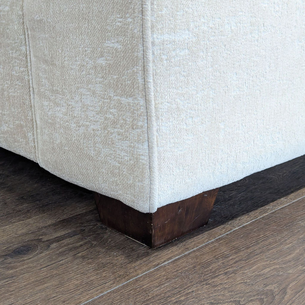 Comfortable neutral lounge chair with soft seat and back cushions, sturdy wooden legs, and supportive armrests.