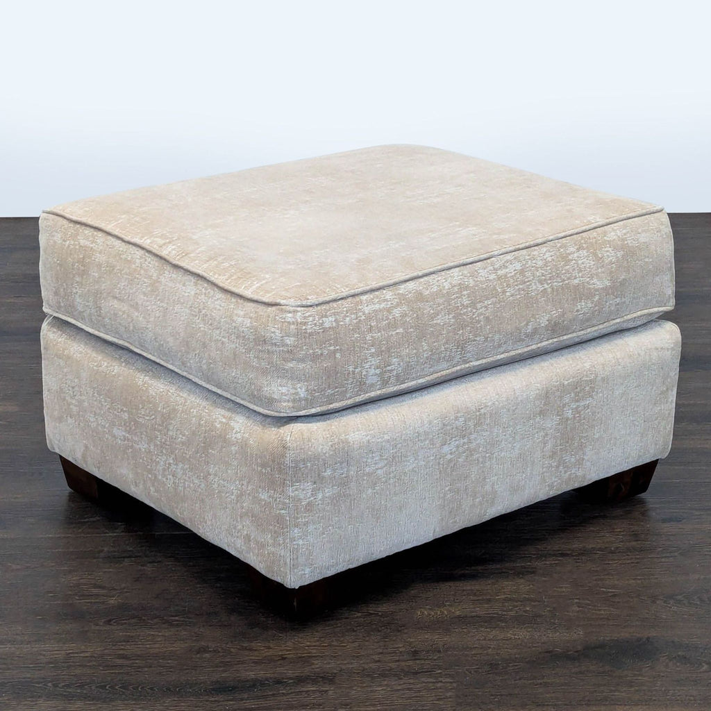 2. Light beige fabric ottoman features a soft top and short wooden feet, perfect for living spaces.