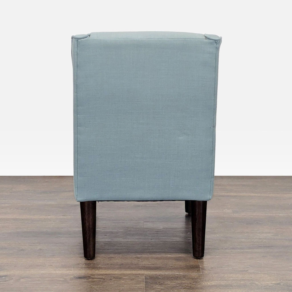 Comfortable Skyline Imports chair in blue fabric with button detailing and dark wooden base.