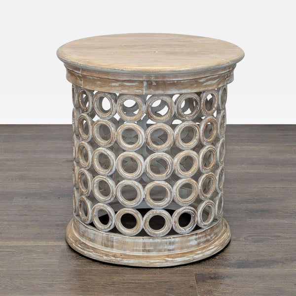 1. Round wooden side table with a distressed finish and a base featuring geometric circular cutout patterns.