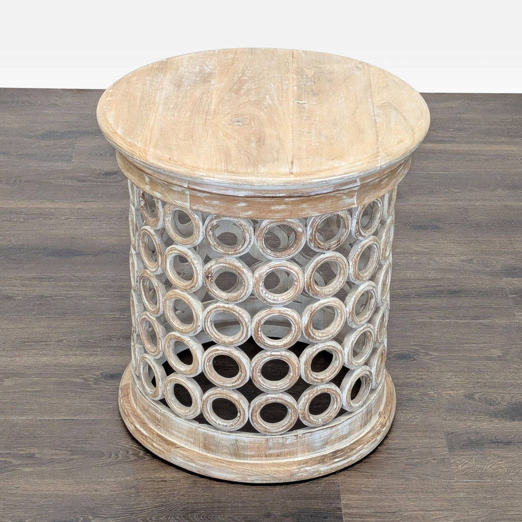 3. Decorative side table, drum-shaped, crafted in wood with repetitive circular cutouts for a unique design.