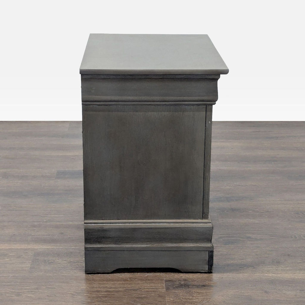 2. Side profile of a dark wood end table with decorative trim, solid panel, and block-style feet.