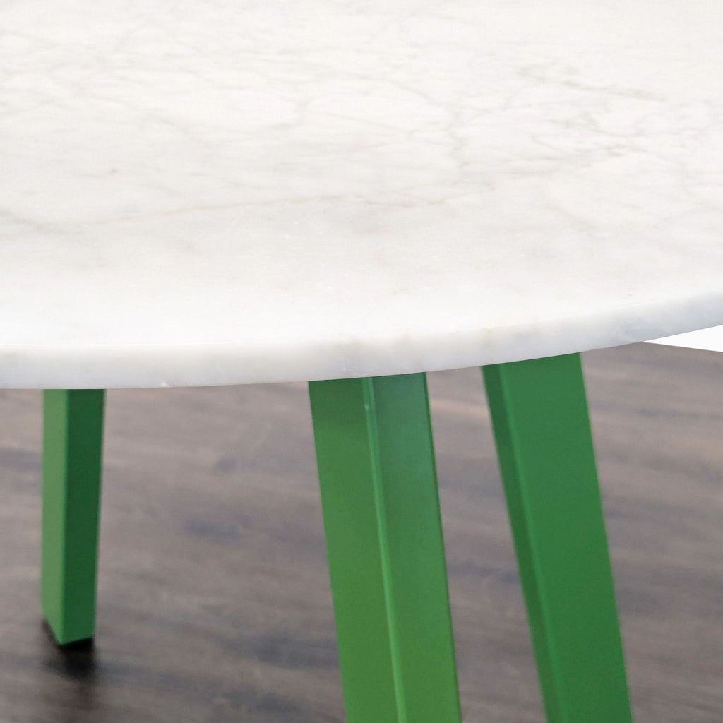 Blu Dot marble table, supported by four powder-coated steel legs, with a refined sculptural design.