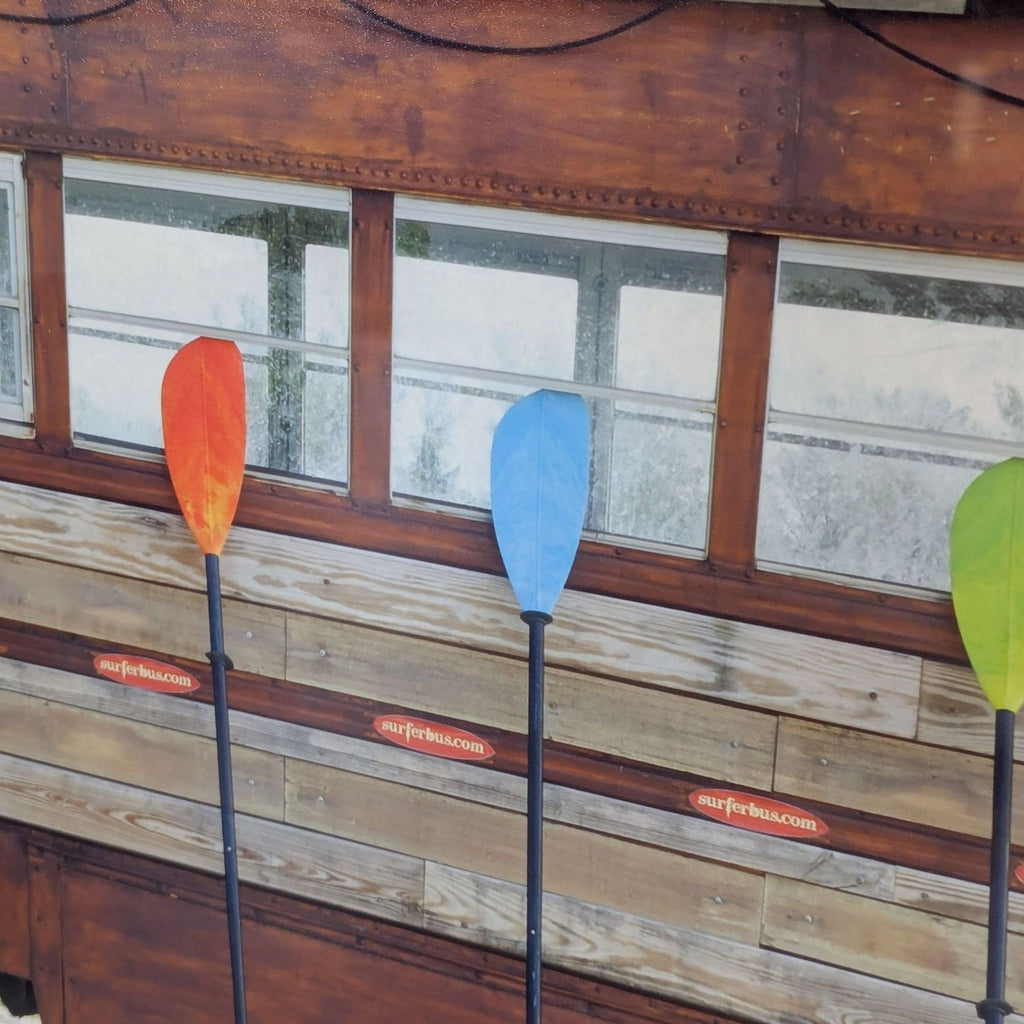 Colorful surf bus with boards and paddles, displayed in a classic frame; ideal coastal-themed wall decor.