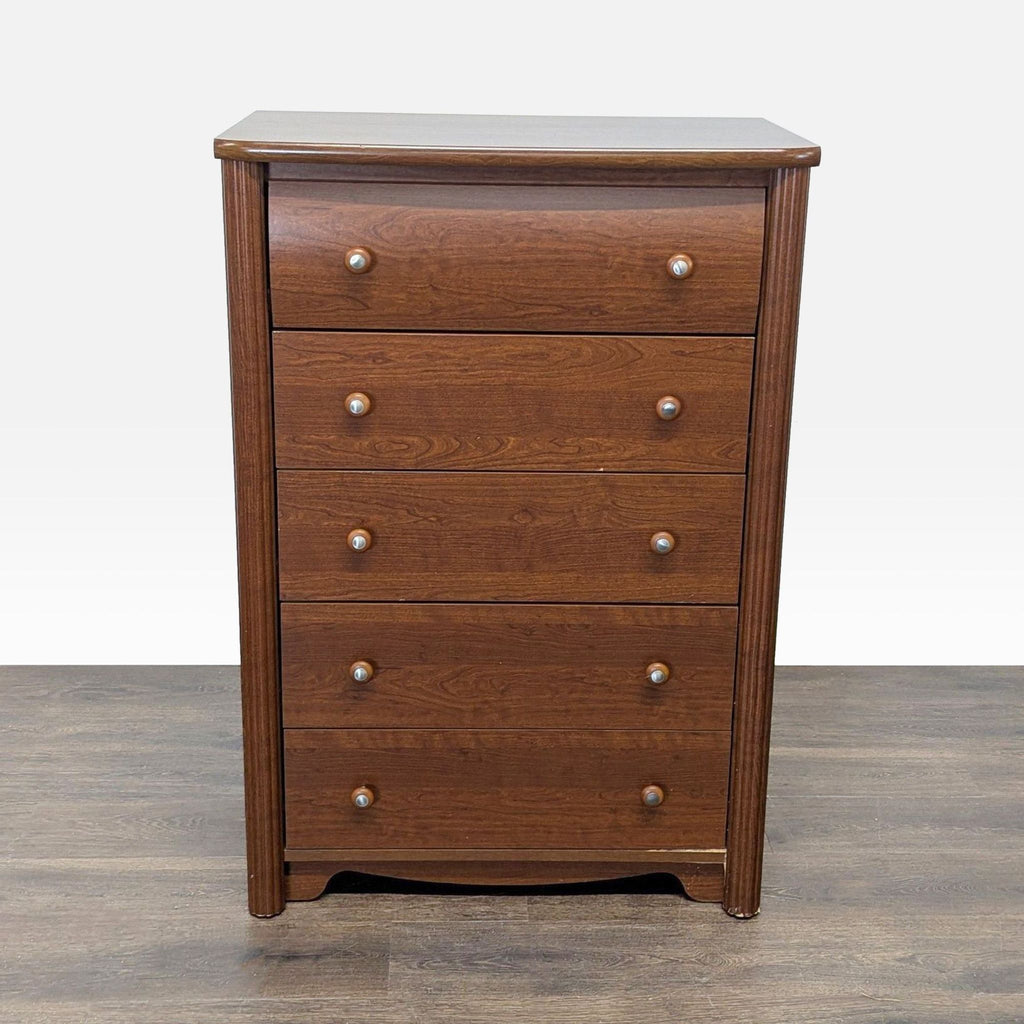 Brown wooden five-drawer dresser by Palliser Furniture with round knobs and classic design.