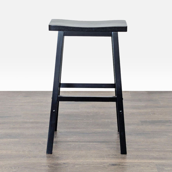 1. Black wooden bar stool with a saddle-shaped seat, viewed from the front on a wood floor.