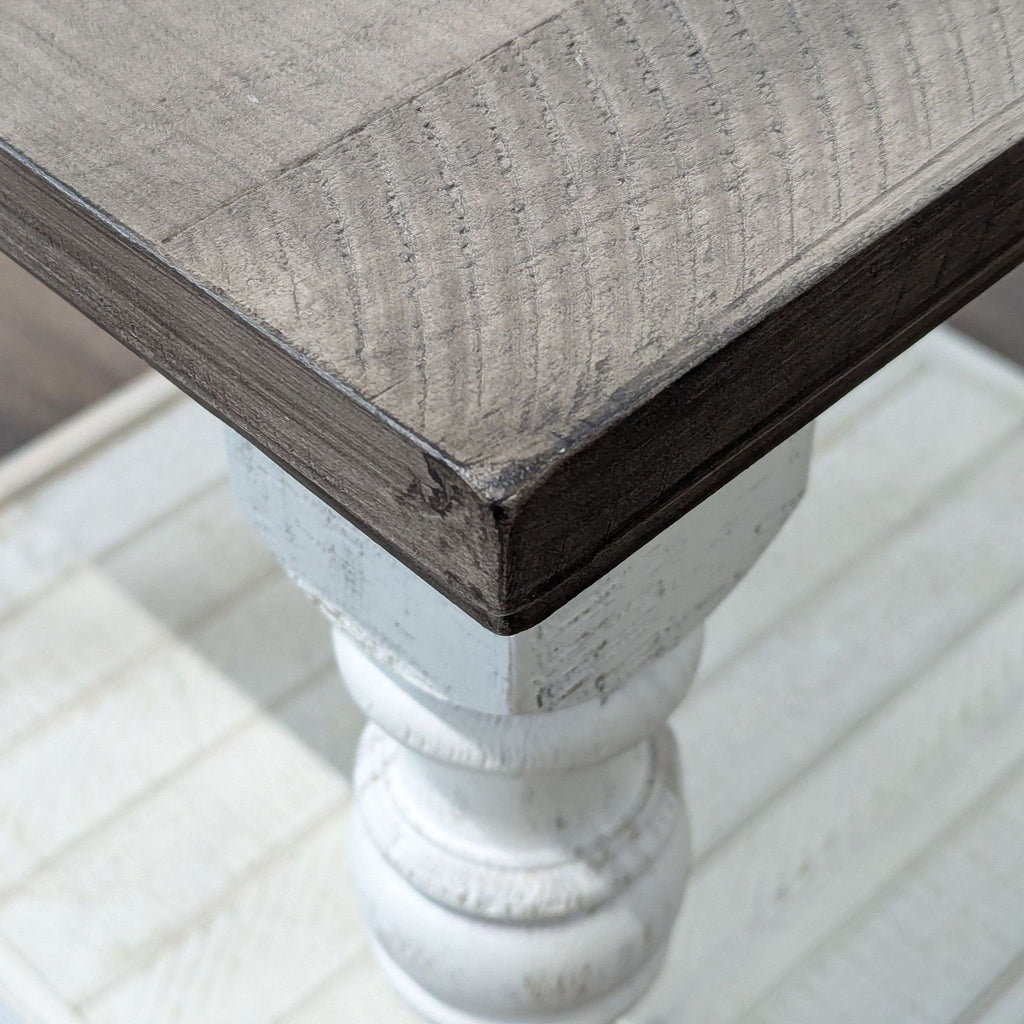Close-up of the Ashley Furniture two tone end table, highlighting the textured pine tabletop and white leg detail.  