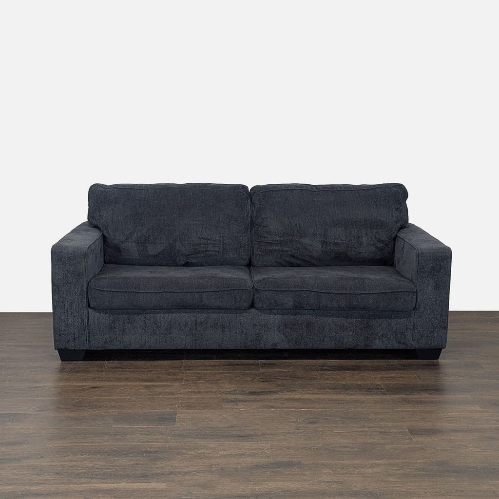 Modern dark gray Ashley Furniture sleeper sofa with plush cushions, converts to a queen bed for guests.