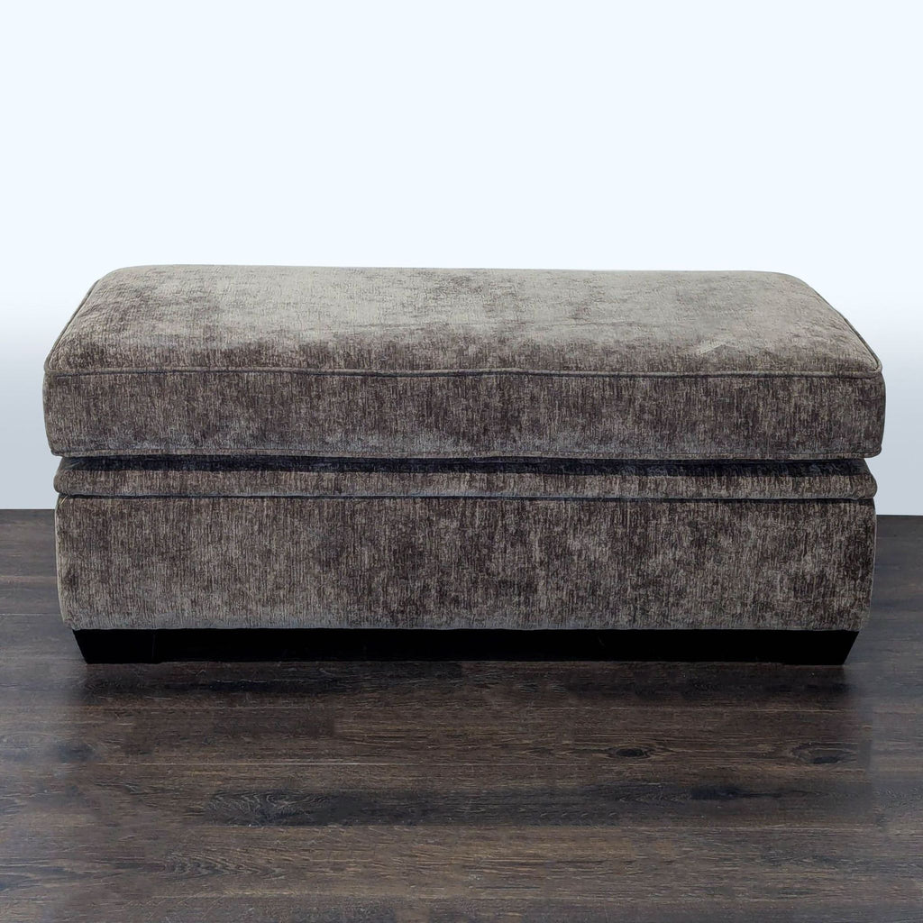 1. Rectangular gray fabric ottoman with a plush top, sitting on dark wood flooring.