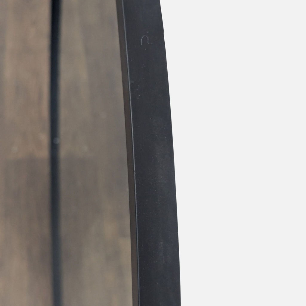 Close-up of the black metal frame edge on an Umbra mirror, showing its sleek minimalist design.  