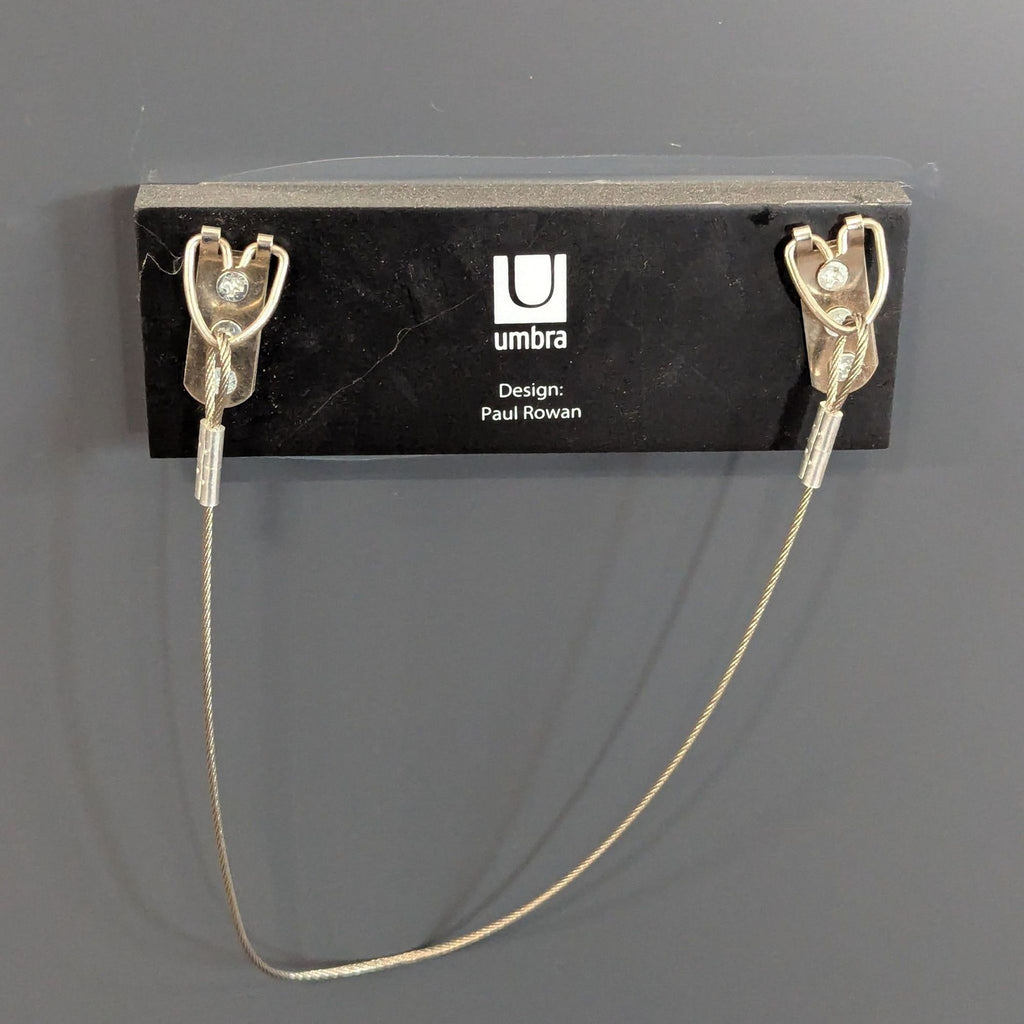 Back view of an Umbra mirror with branded mounting hardware and a sturdy hanging wire for wall installation.