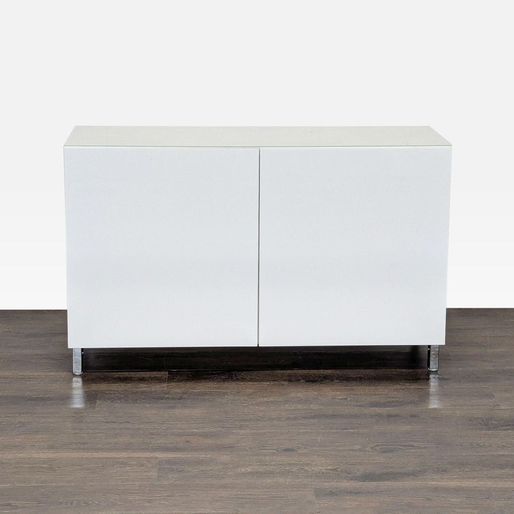 White Ikea cabinet with two doors, adjustable shelves, and metal legs, ideal for organized home storage.