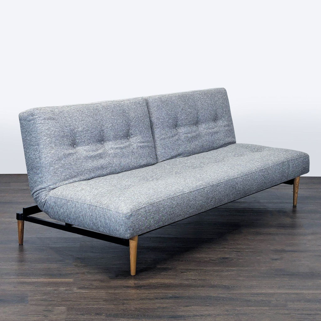3. Tufted gray West Elm sleeper sofa shown with sturdy wooden legs, modern look, perfect for versatile seating.