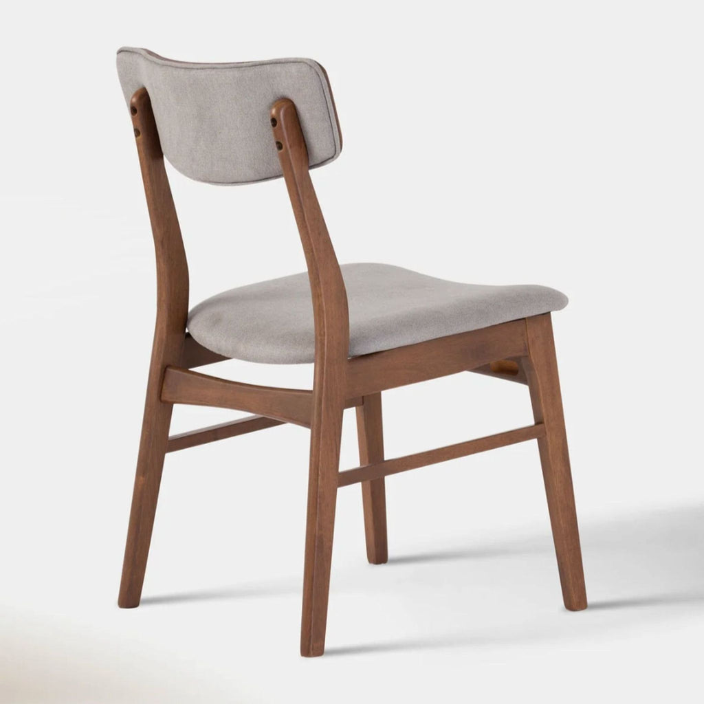 Angled back view of a Hoft Home dining chair, showing smoke-grey cushioned seat and walnut-finish wood frame.
