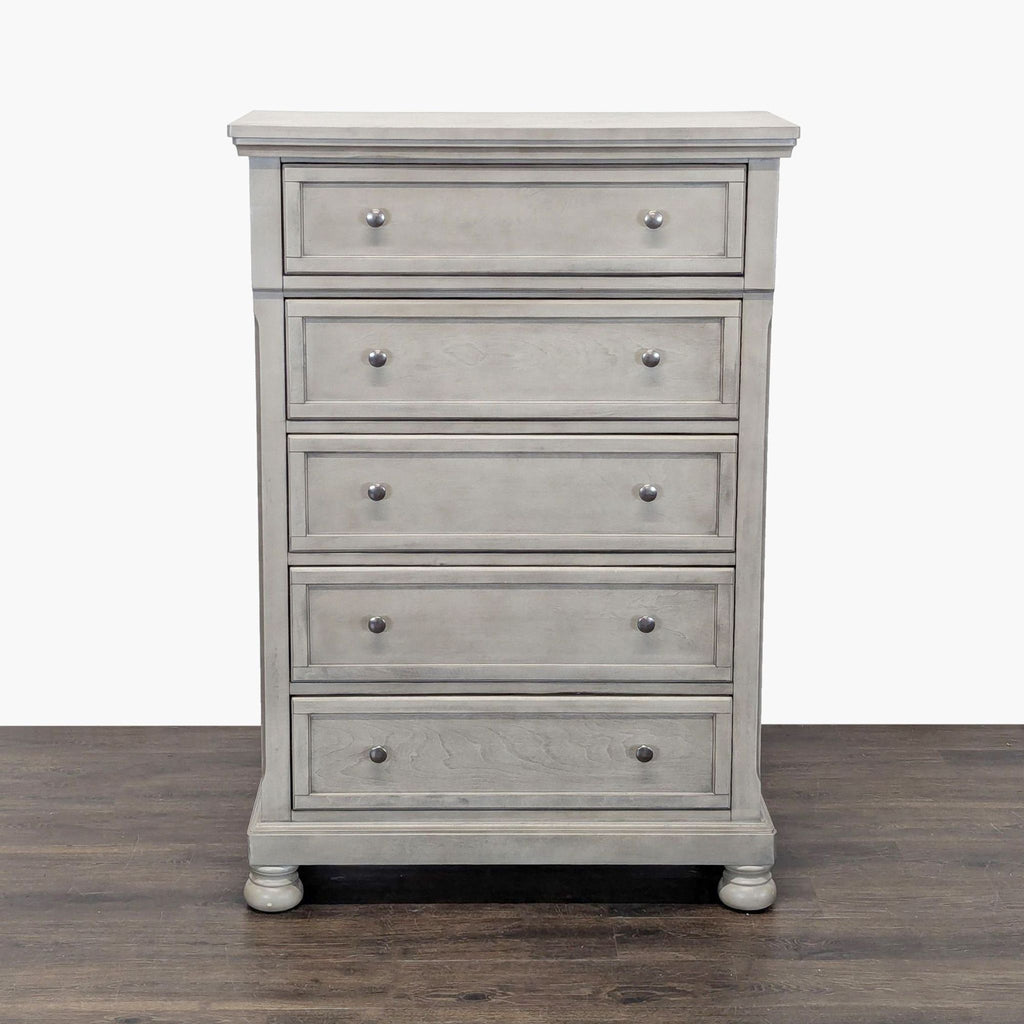 Ashley Furniture light gray dresser with five drawers and round knobs, ideal for bedroom storage.