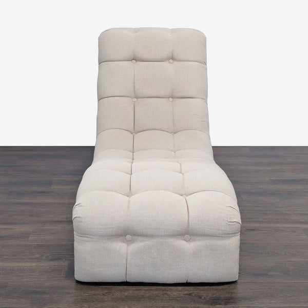 1. Front view of a modern, tufted beige chaise lounge with a low, curved design on dark wood flooring.